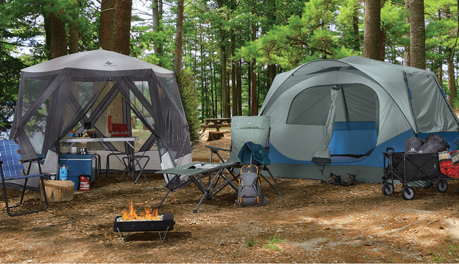 Terrain de camping dans un endroit boisé avec 2 tentes, un fauteuil en toile Outbound, une chaise longue réglable à 3 positions Woods Ashcroft et un foyer de camping portatif Outbound.