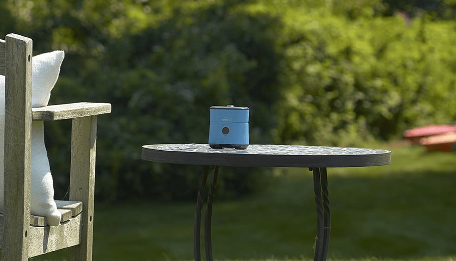 Thermacell Radius Mosquito Repeller on a small table in a backyard.