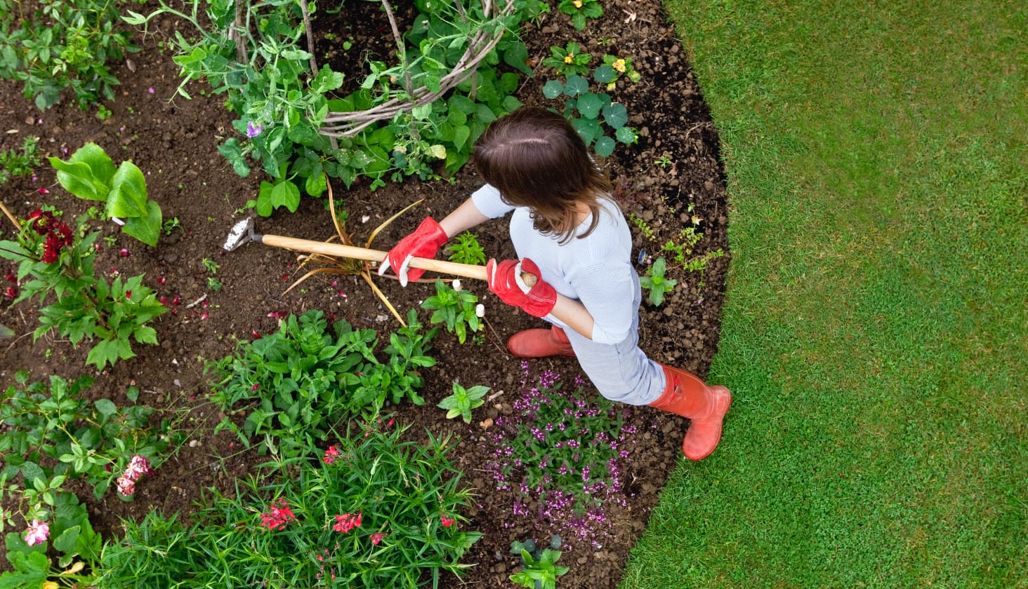 Woman with red gloves using garden shovel in soil