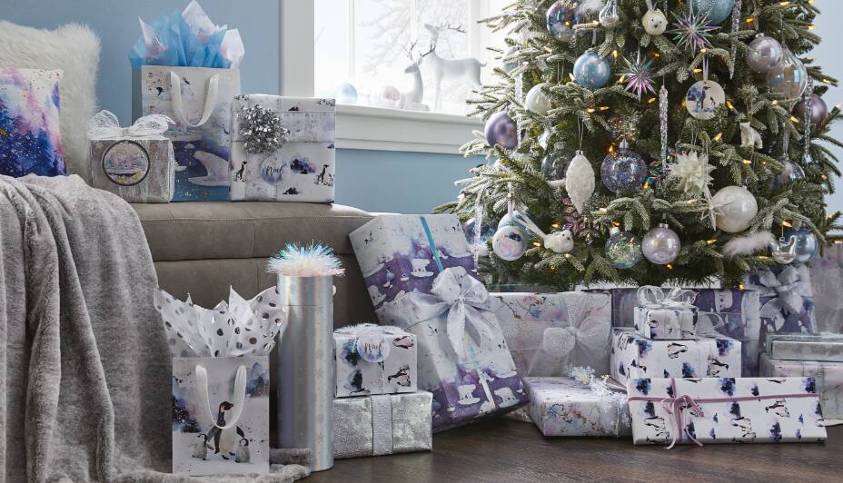 Holiday gifts and gift bags in the Canvas Nordic Lights wrapping collection under a Christmas tree.