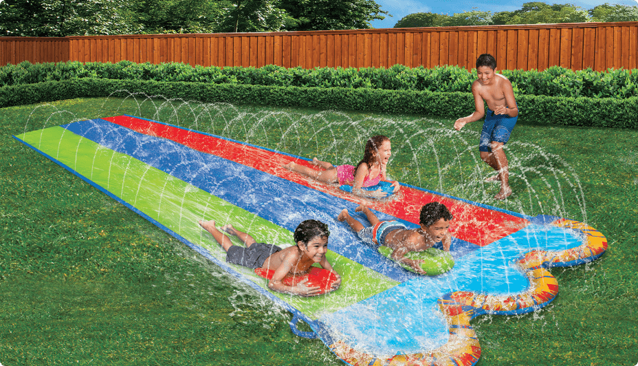 Kids playing outside on a backyard water slide.