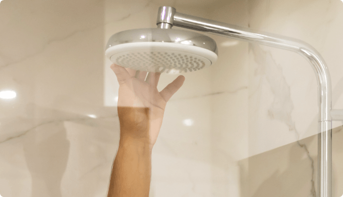 Close-up of hands using a wrench on a showerhead.