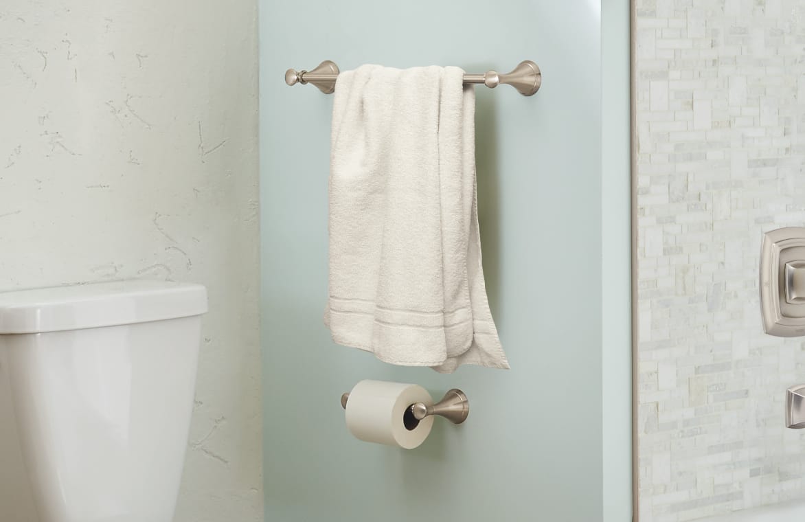 A towel bar with a towel and toilet paper holder, in a bathroom. 