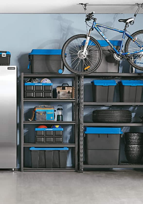 Grande armoire de la série inoxydable de Maximum, deux grandes tablettes noires avec bacs de rangement noirs avec couvercles bleus, vélo suspendu d’un support de plafond dans un garage.