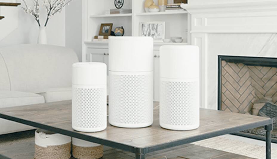 Three NOMA iQTM Air purifiers in different sizes displayed on a living room table