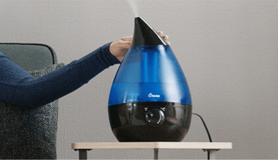Woman adjusting a humidifier on a side table.