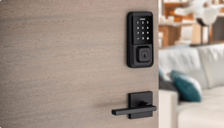 A black security keypad and matching door handle mounted on a brown door opening onto the inside of a home.