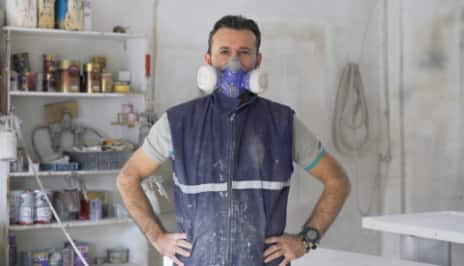 Un homme portant un masque pour le protéger contre les vapeurs de peinture.  