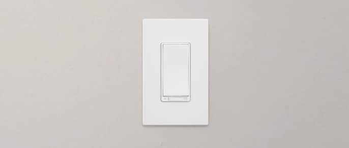 A white Globe Smart Dimmer switch mounted on a grey wall inside a home.