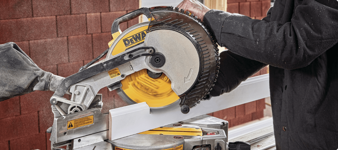 Man using mitre saw to cut a wooden panel. 