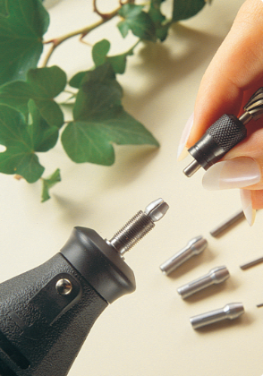 Rotary tool accessories are sitting on a tabletop with someone changing a tool part