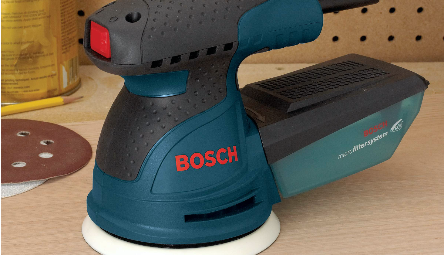 Bosch ROS10 Palm Sander and sanding disc on smooth wood surface.