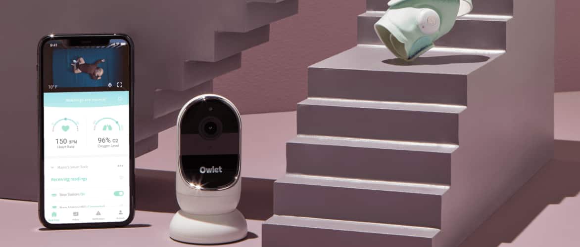 Téléphone intelligent à côté d’une caméra de sécurité Owlet.