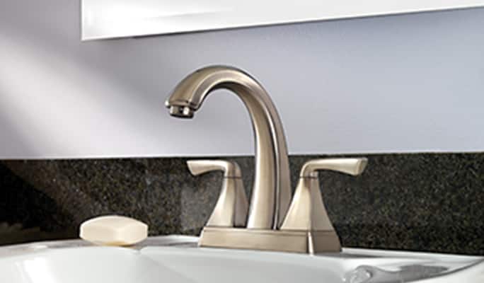 Brass-coloured bathroom faucet on a white sink.