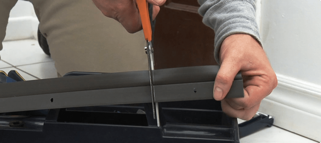 Man cutting rubber weatherstrip with a pair of scissors.