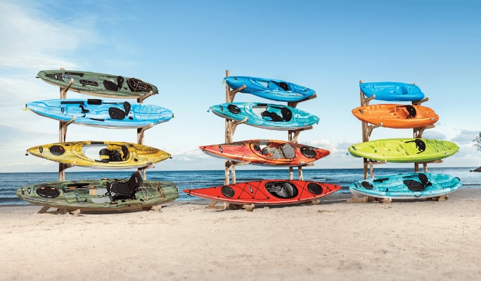 Four Kayaks on a rack arranged from smallest to largest in blue, orange, yellow, and green.