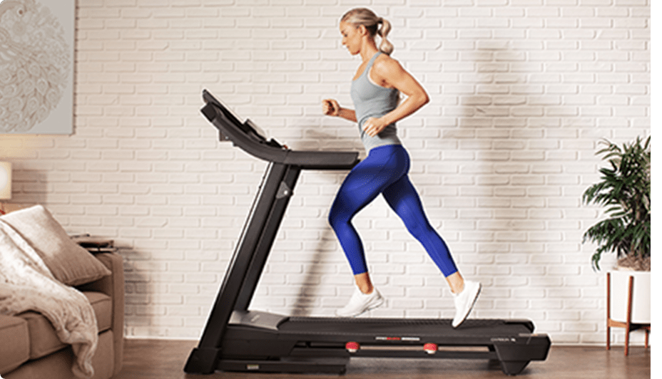 Woman runs on a treadmill in a living room.