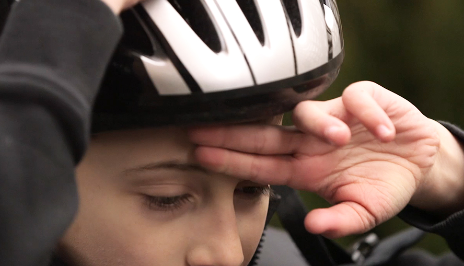 Boy measuring helmet above the eyebrows with two fingers.