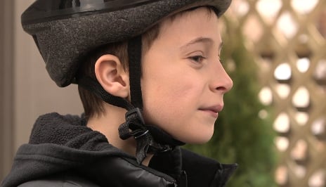 Boy wearing helmet with strap in V-form under ear.