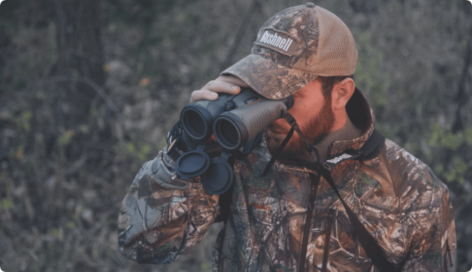 Man in camouflage looking through binoculars