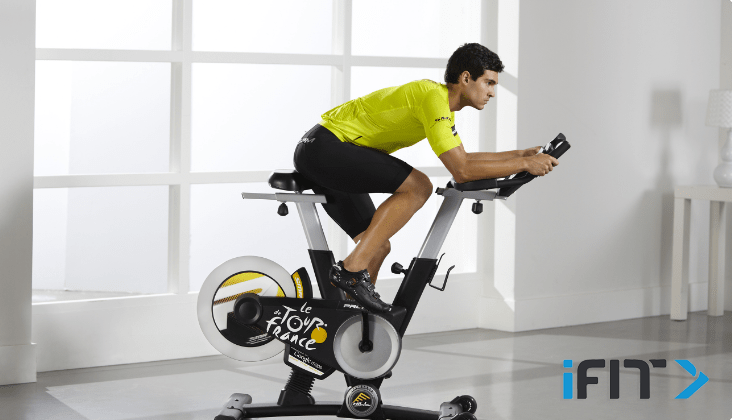 Woman running on treadmill as iFIT interactive training session plays on her screen.  