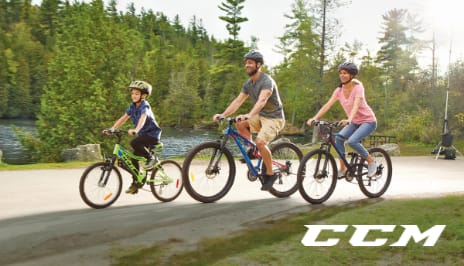 A family of three ride CCM bicycles along a scenic trail.