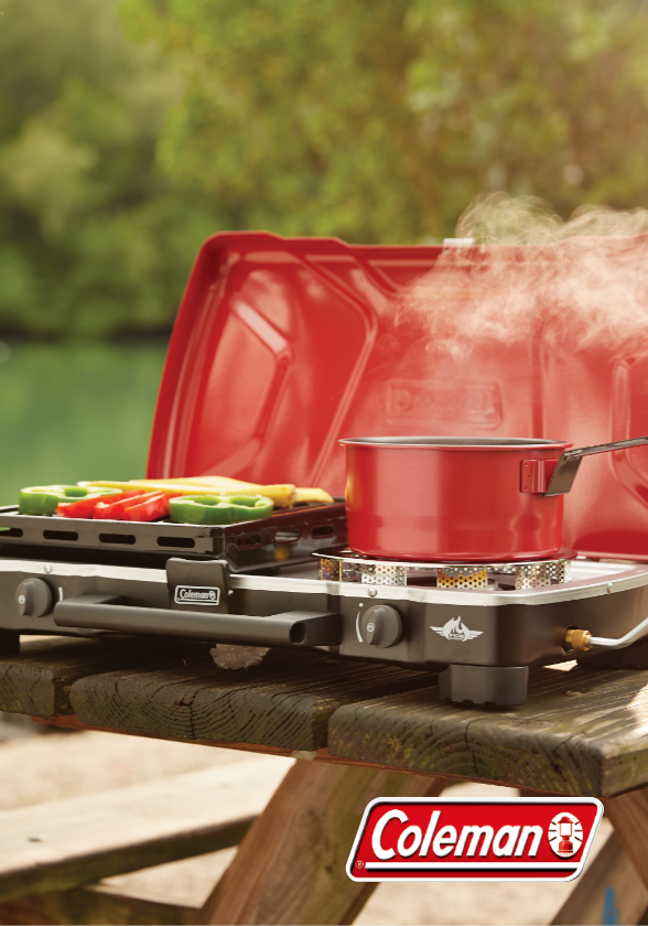 Red Coleman burner stove with pot and vegetables.