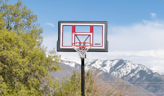 A basketball backboard stands against a backdrop of distant mountains.