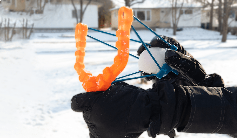 Personne sur le point de lancer une boule de neige à l’aide d’un lanceur de boules de neige Snow Sling.
