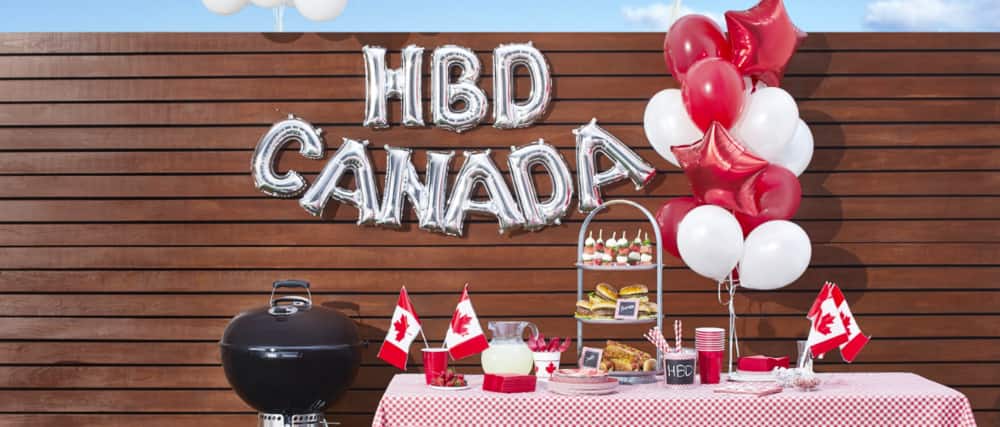 Canada Day balloons, flags and other party décor on a table. 