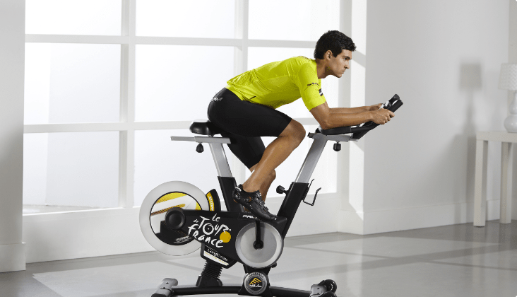 Une femme s’exerce sur un tapis roulant tout en participant à une session d'entraînement interactive iFIT diffusée sur son écran.  