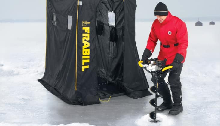 Un homme en train de percer un trou dans la glace avec une tarière.
