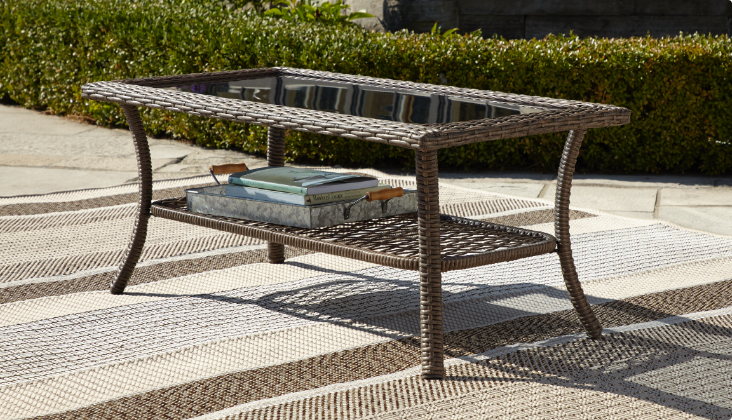 Table basse d’extérieur en osier à dessus en verre et compartiment de rangement inférieur