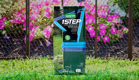 Bag of Golfgreen’s 1-Step product set against a grassy backdrop which also contains a chain fenced garden. 