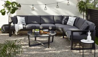 Grey Whistler sectional with white cushions, glass top coffee table and black side table with accessories