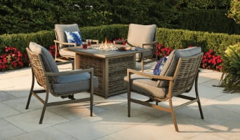 Sandbanks 5-piece set with 4 wicker rocking armchairs with tan coloured cushions and a firepit table on a patio