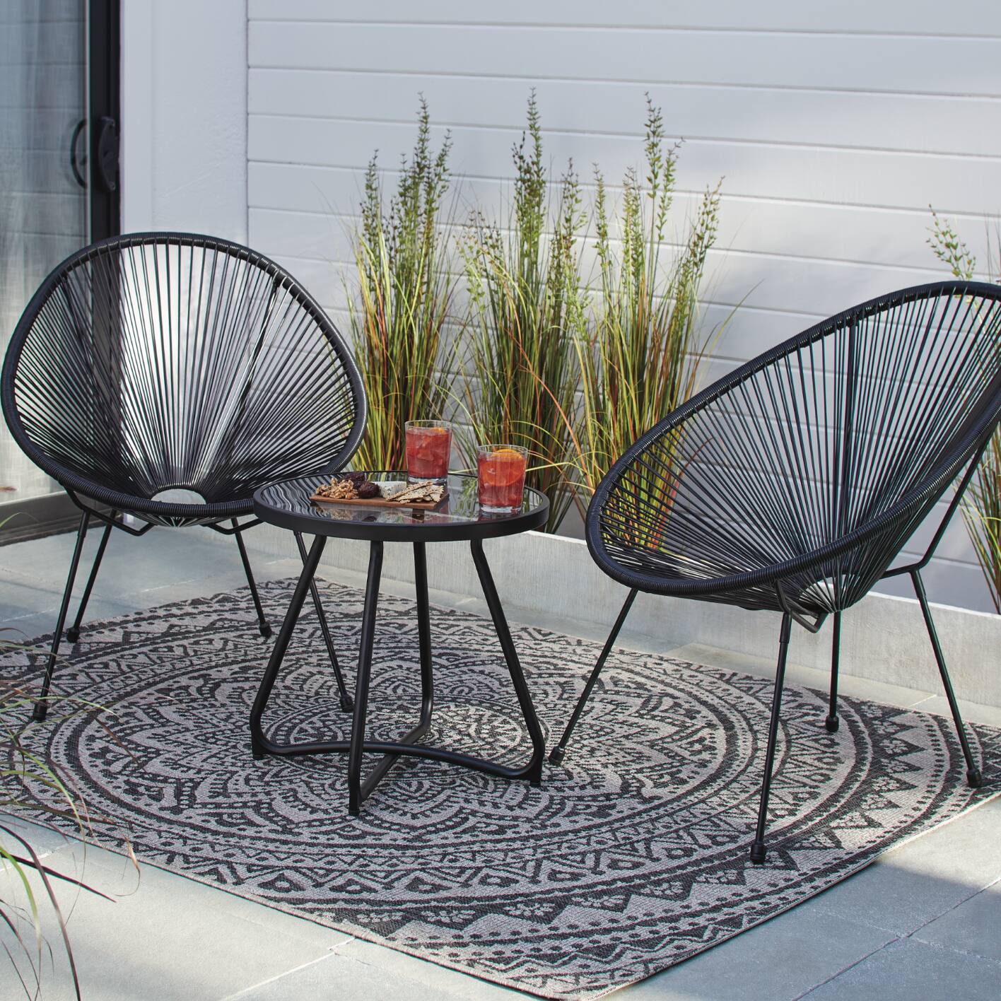 Canvas Acapulco Chat Set including 2 chairs and a table in black set up on a patio.