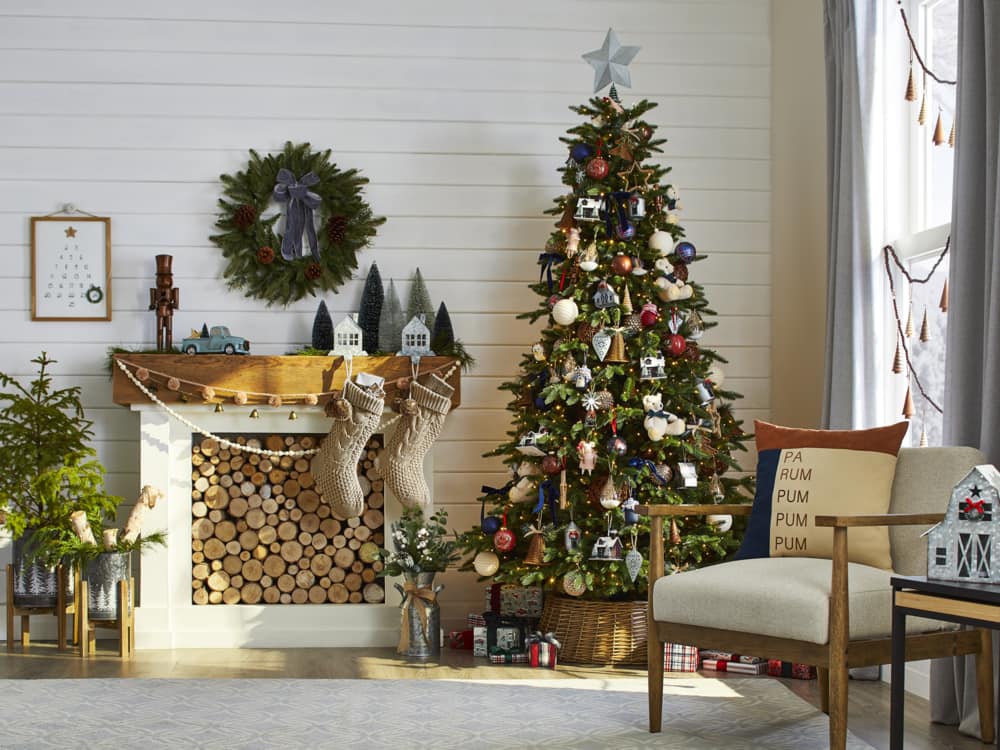 Un coin salon muni de décorations de Noël rustiques et chaleureuses, y compris un arbre avec des ornements, des bas, une couronne et un manteau de cheminée de Noël.