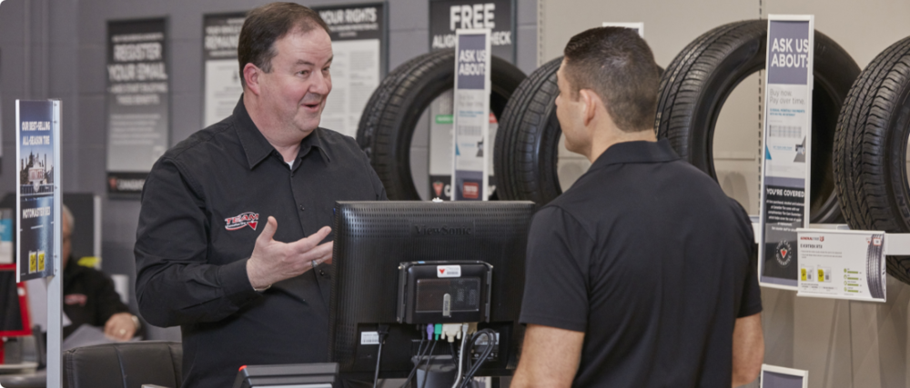 A friendly Canadian Tire service advisor interacting with a customer. 