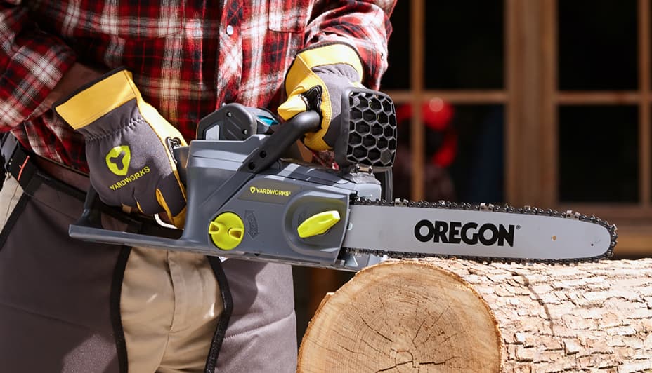 Person holding a Yardworks chainsaw and cutting a tree