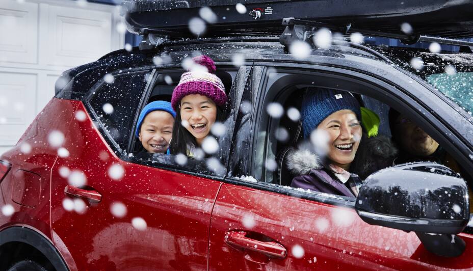 Famille assise dans une voiture rouge avec les fenêtres baissées
