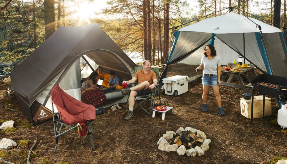 Des gens rassemblés autour de 2 tentes montées sur un terrain de camping.