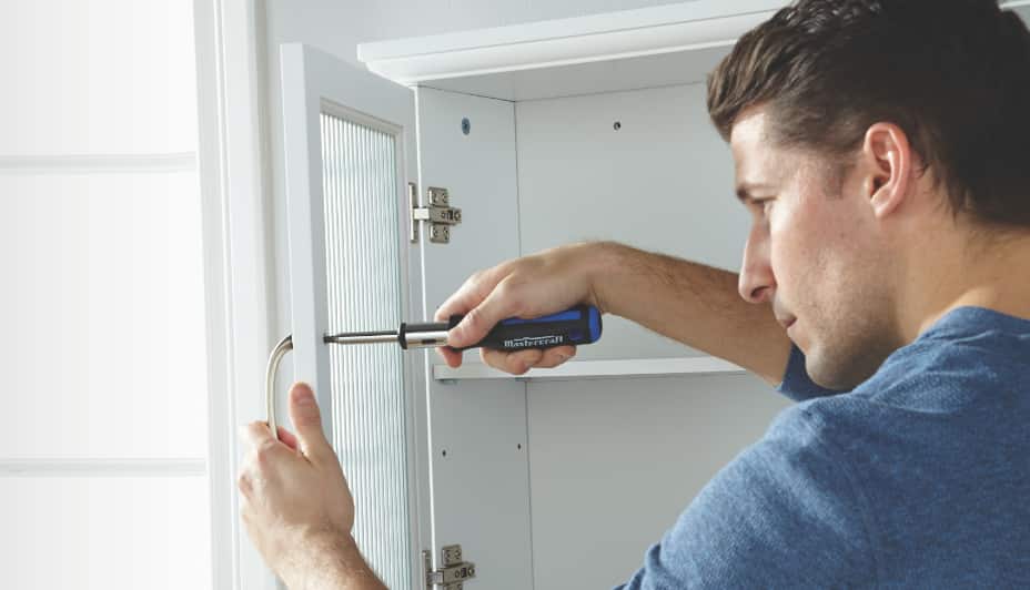 Un homme utilisant un tournevis sur une armoire de cuisine