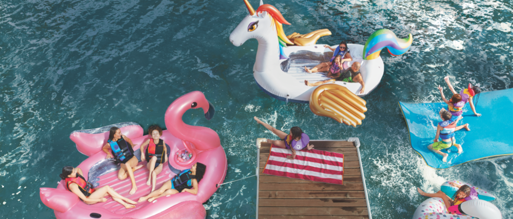 Family enjoying fun on the lake on unicorn and flamingo floats and mats.