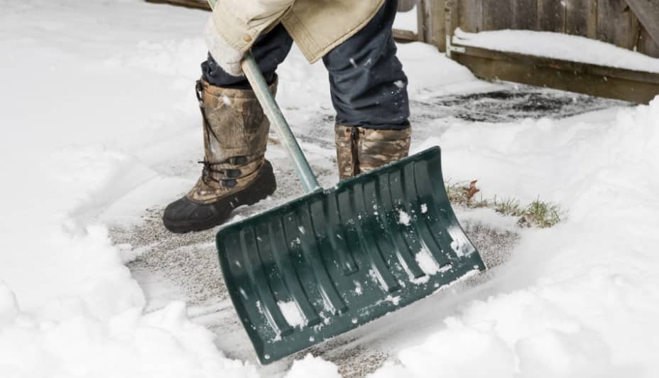 Un homme utilisant une pelle pour enlever la neige d’un trottoir