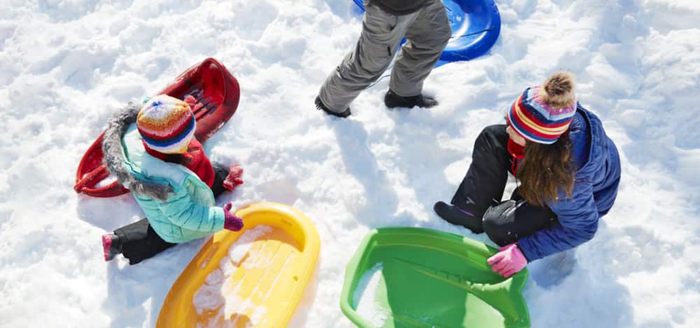 Enfants jouant dans la neige avec des toboggans.