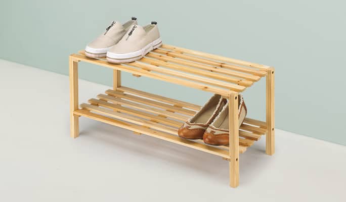 Range-chaussures en bois avec deux baskets exposés.