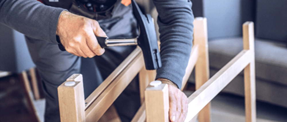 A man hammers a floor protector into the leg of a furniture item.