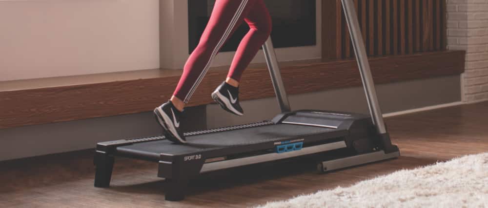 Woman running on treadmill in home living room gym.