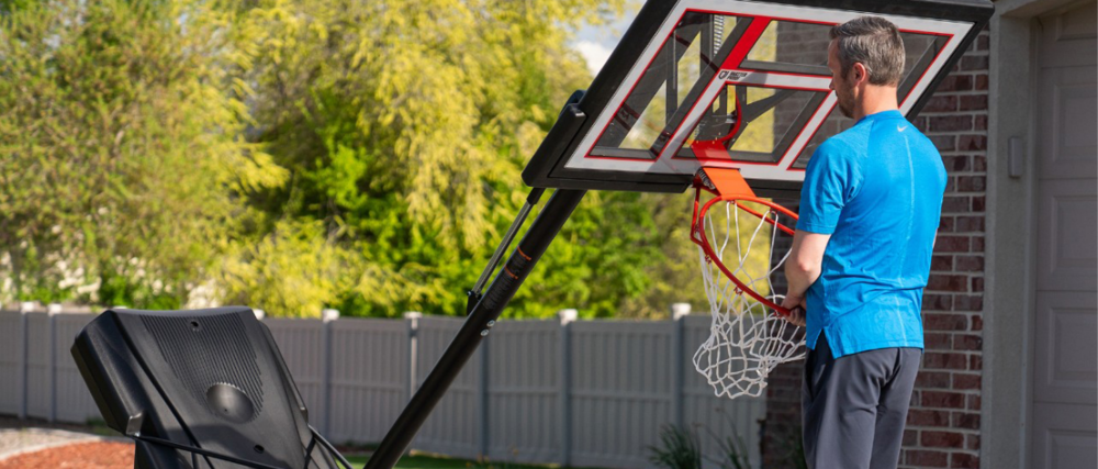 Man assembling new basketball net on home driveway.